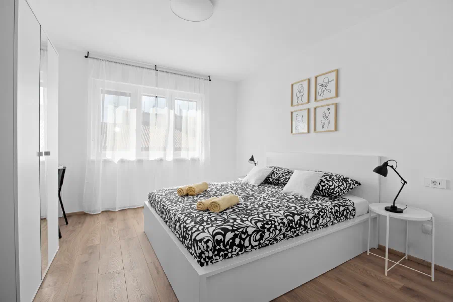 A bright bedroom with natural wood and white linens